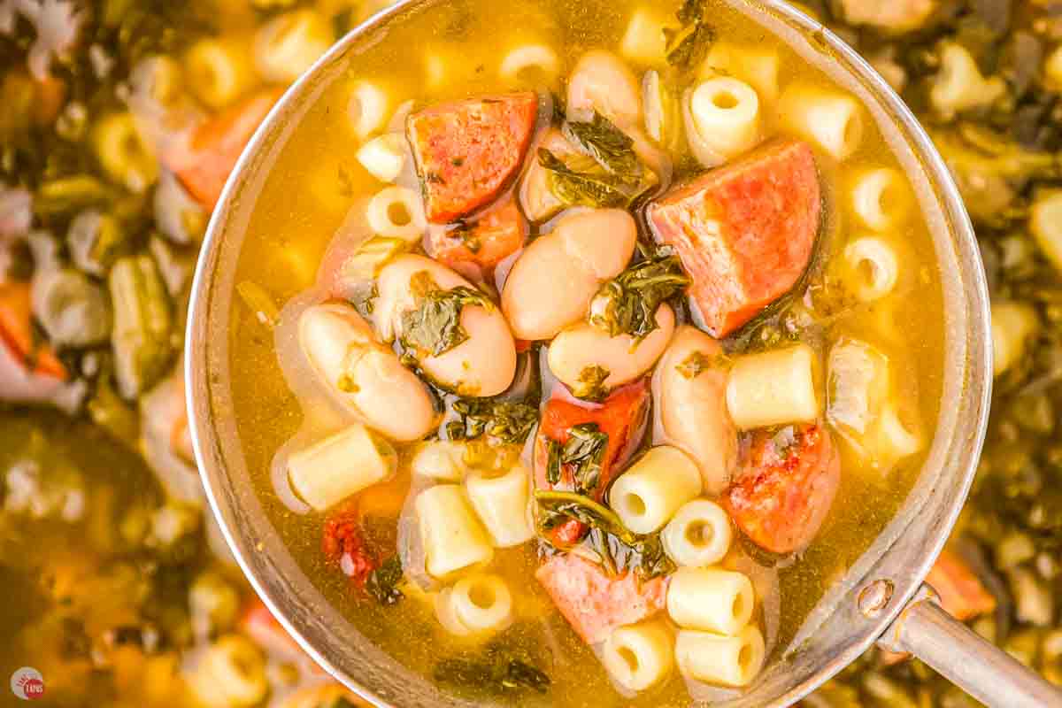 close up of ladle of soup with small pasta noodles