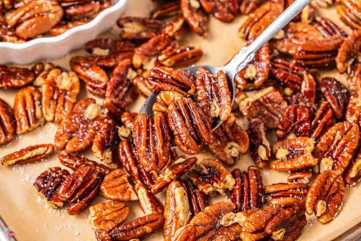 spoon of toasted pecans on a baking sheet