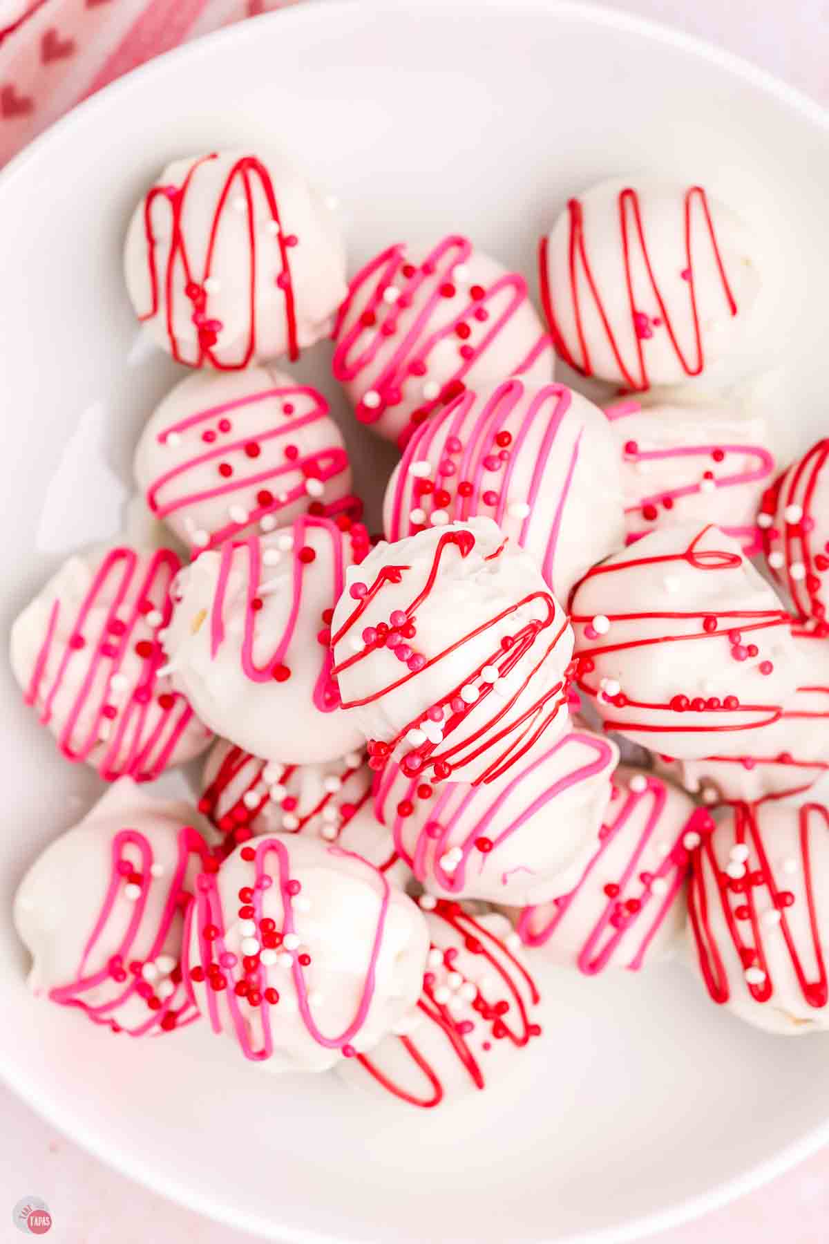 stack of Oreo balls decorated with red and pink sprinkles on a white plate