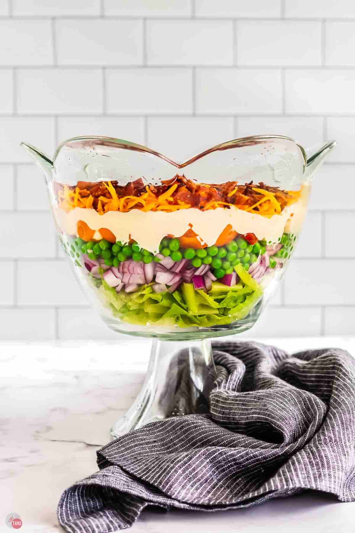 trifle bowl with a layered salad and a blue napkin