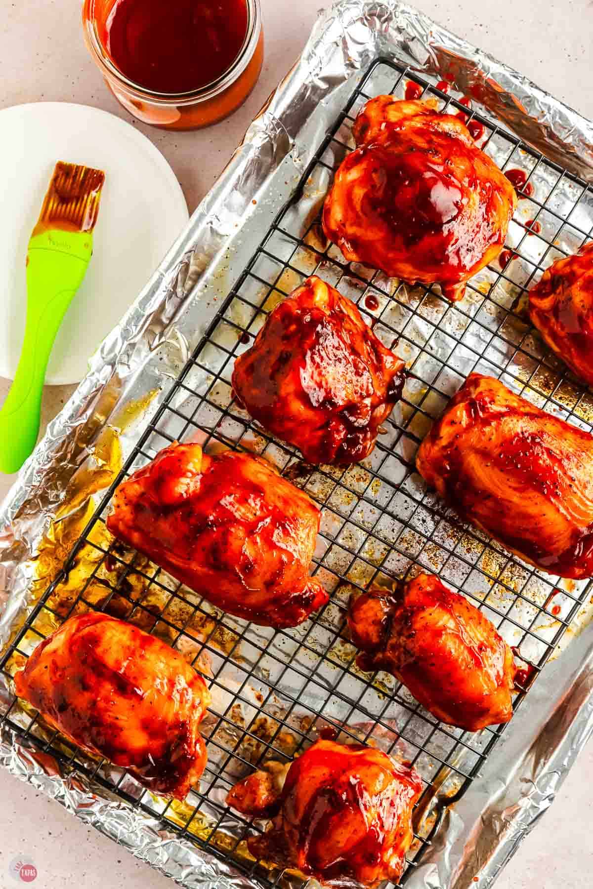 chicken thighs covered with bbq sauce on a baking sheet