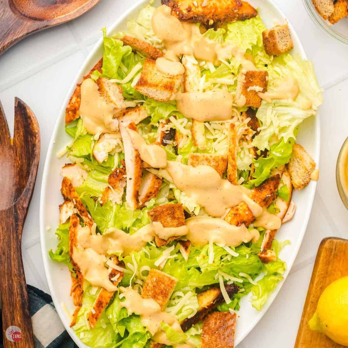 platter of salad, dressing, croutons, and sliced chicken