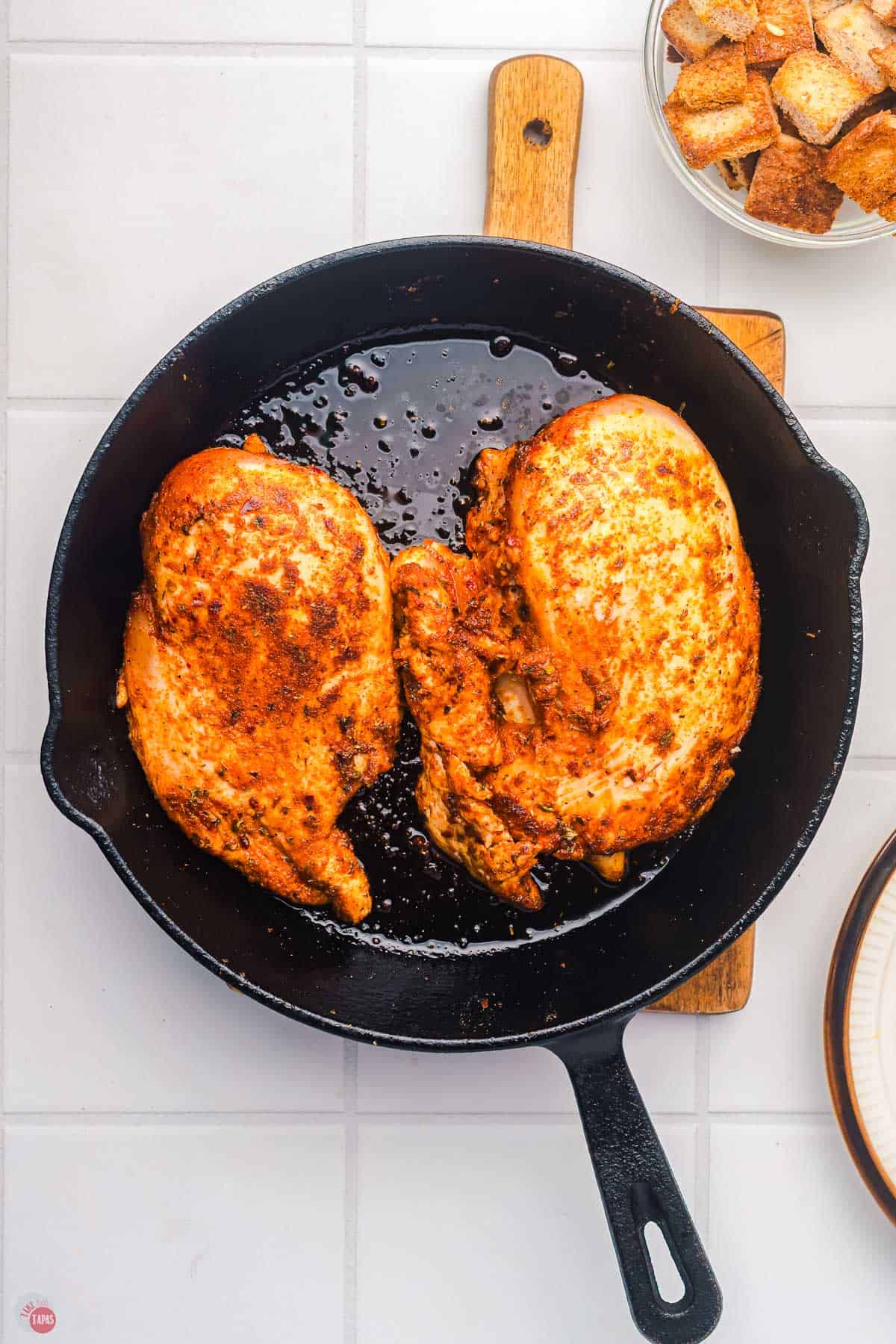 chicken breasts cooking in a cast iron skillet