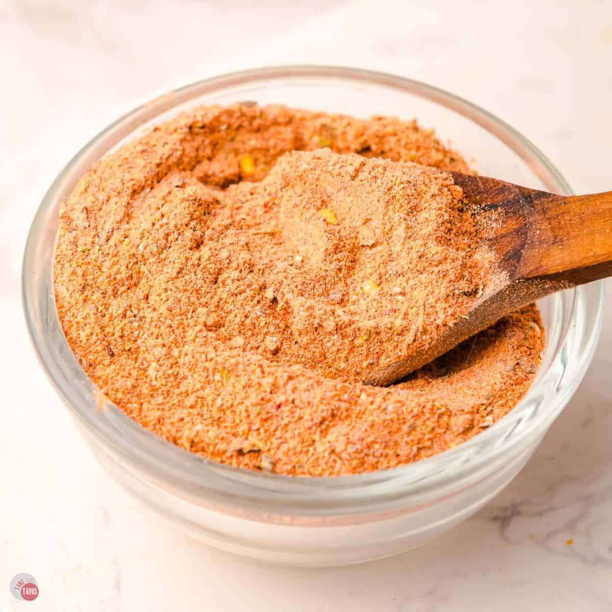 clear bowl of spices with a small wood spoon