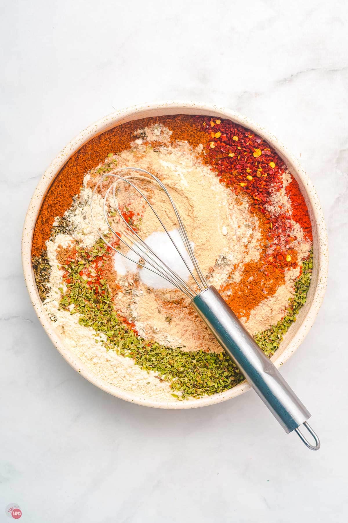 whisk mixing spices on a white plate
