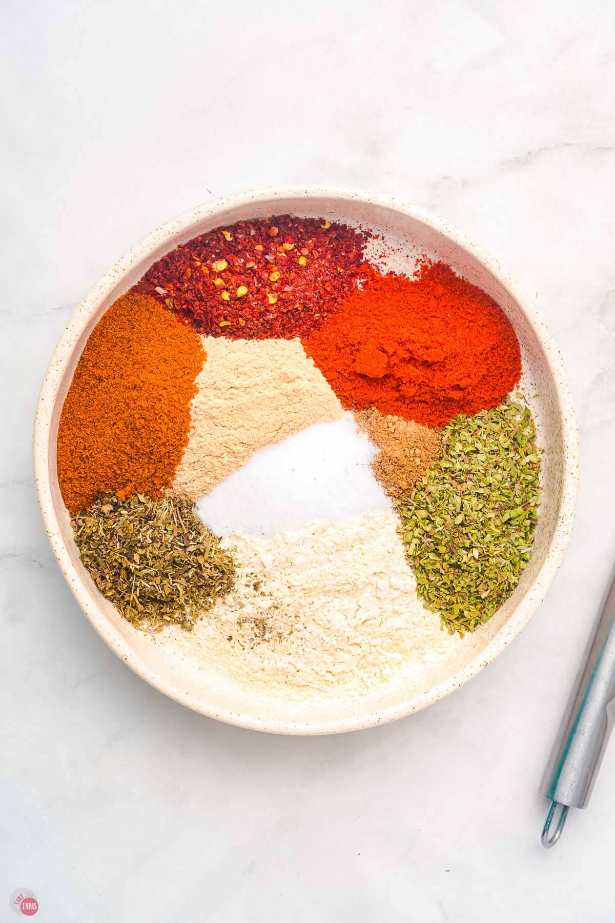 individual spices in mounds on a white plate