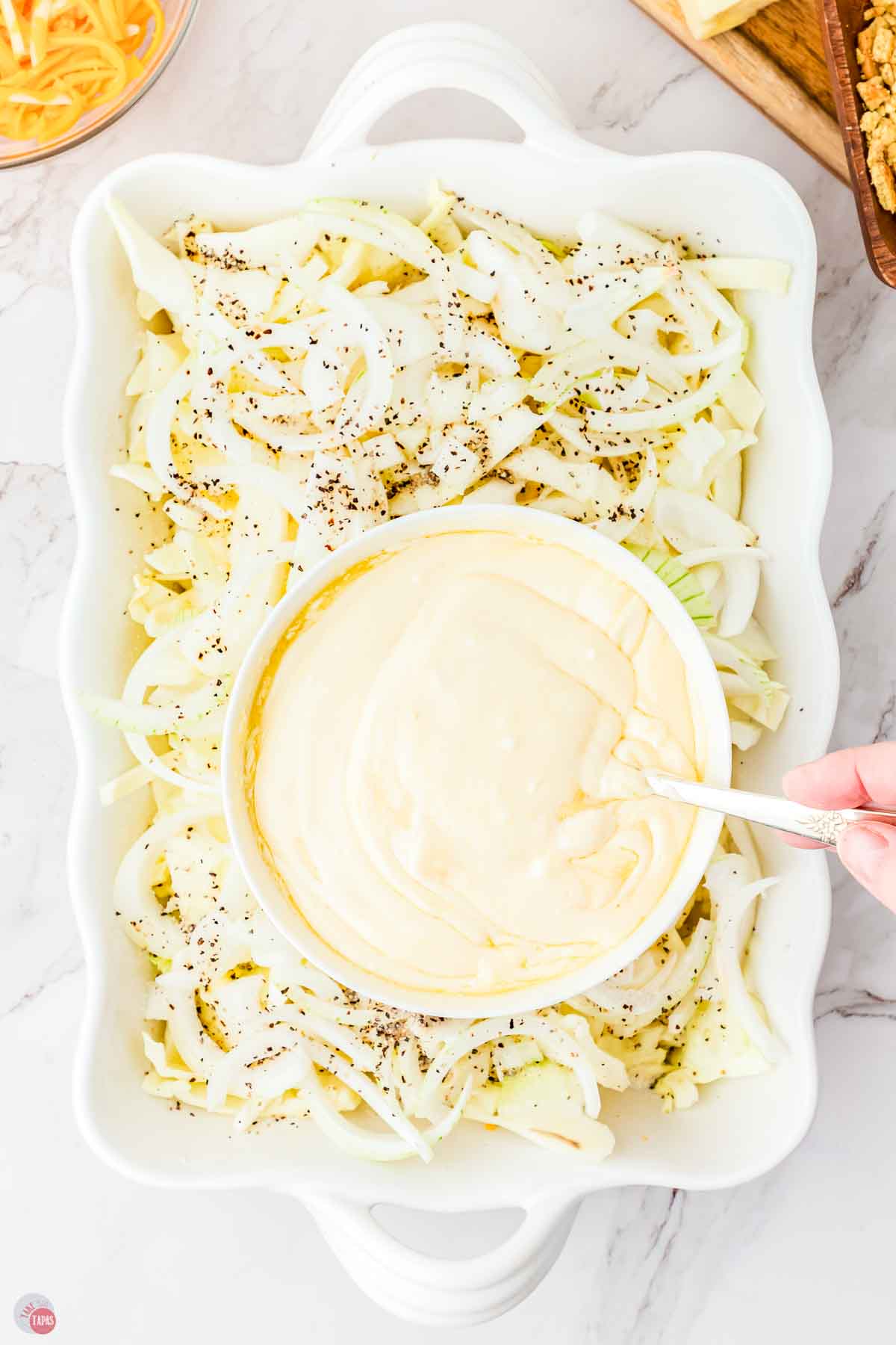 shredded cabbage in a dish with a bowl of white sauce on top