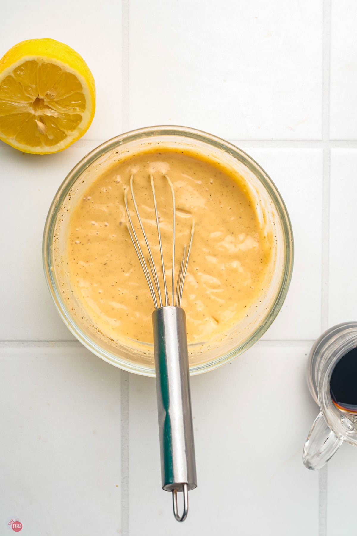 bowl of salad dressing with a whisk in it