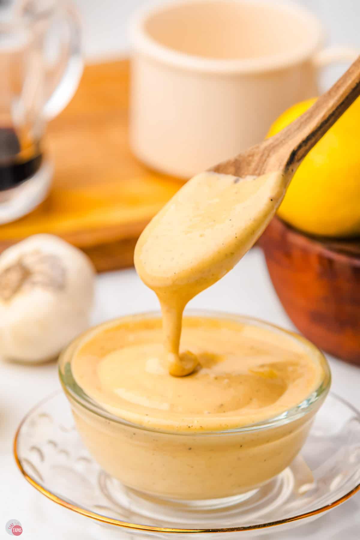 wood spoon pouring caesar salad dressing into a clear jar