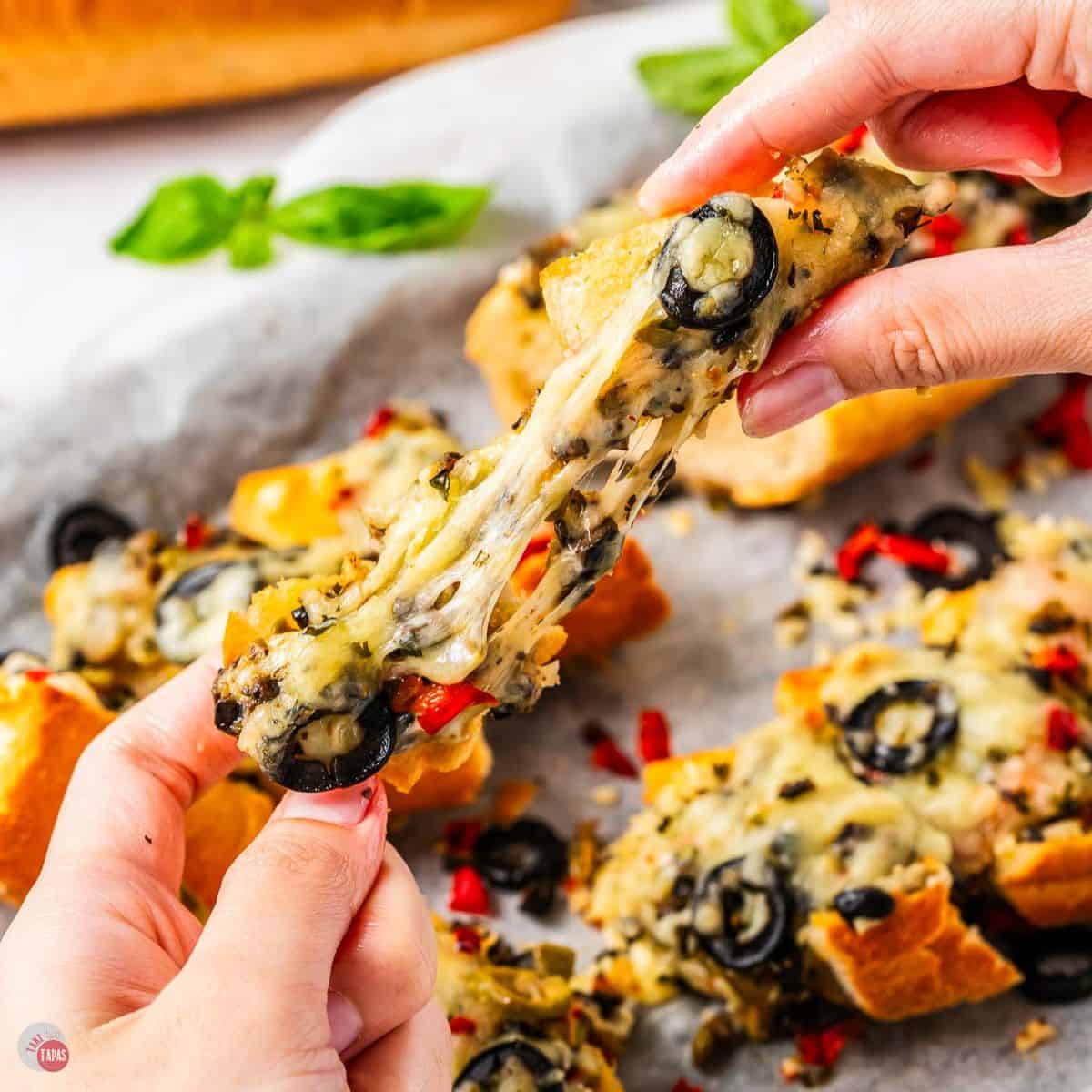 two hands pulling cheese bread apart