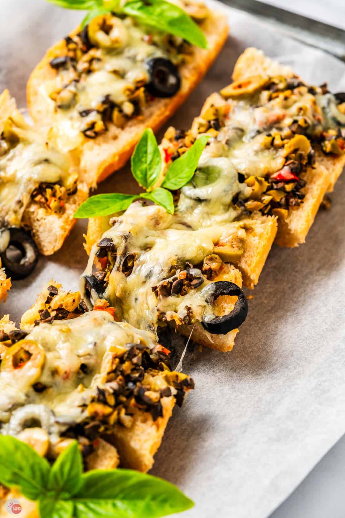 parchment paper with cheese bread on it cut into slices