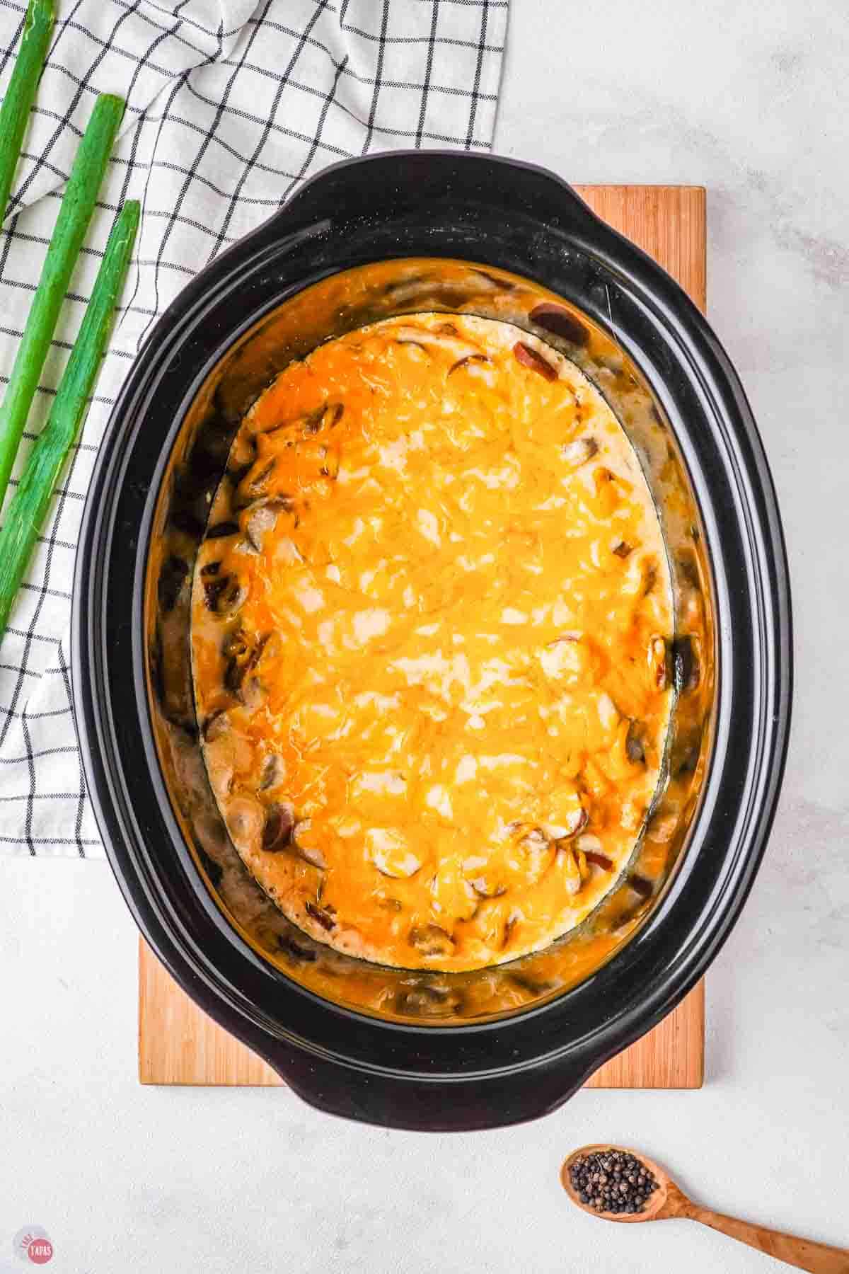 melted cheese and pierogis in a black slow cooker