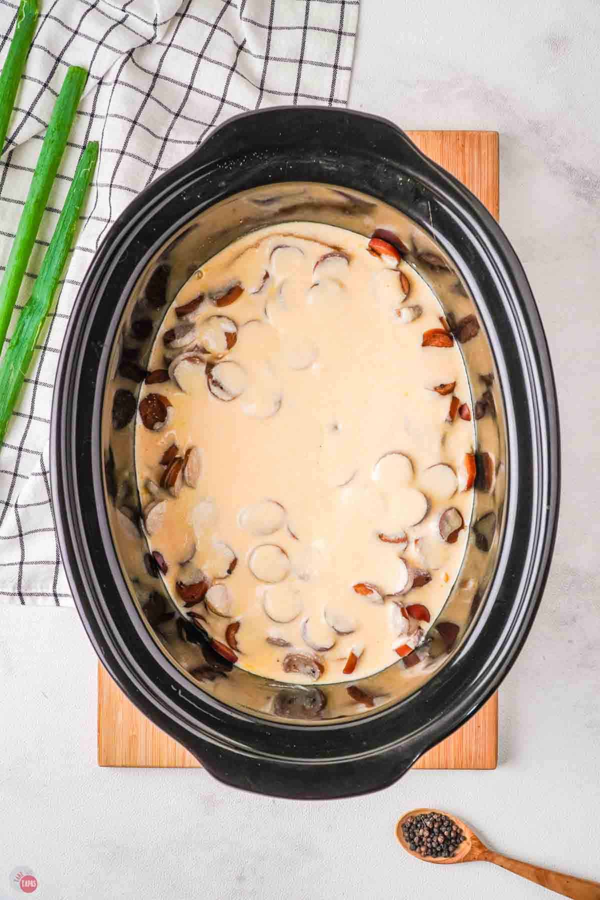 crock pot with sausage and a cream sauce on it