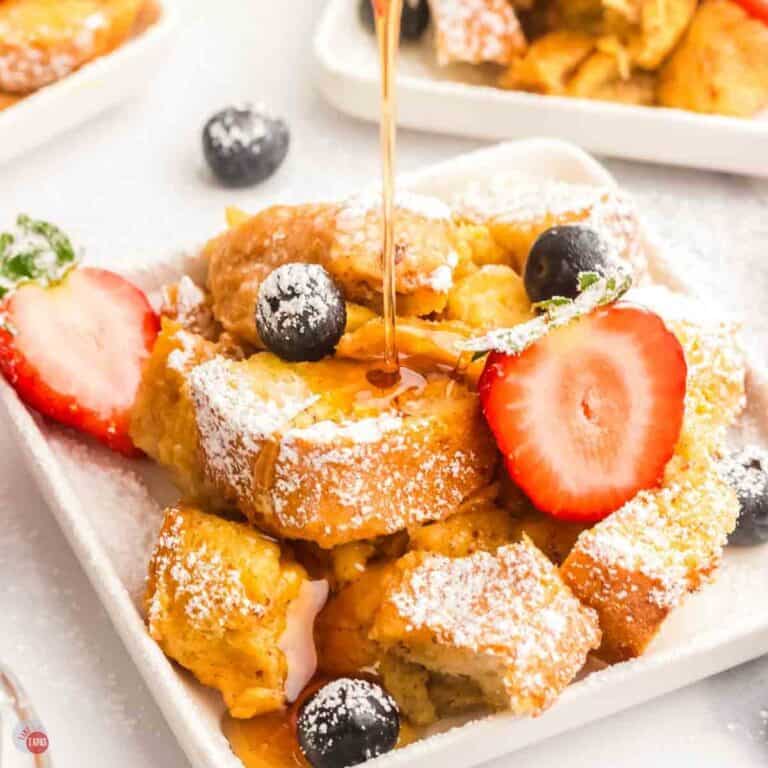 plate of french toast casserole with strawberries and powdered sugar