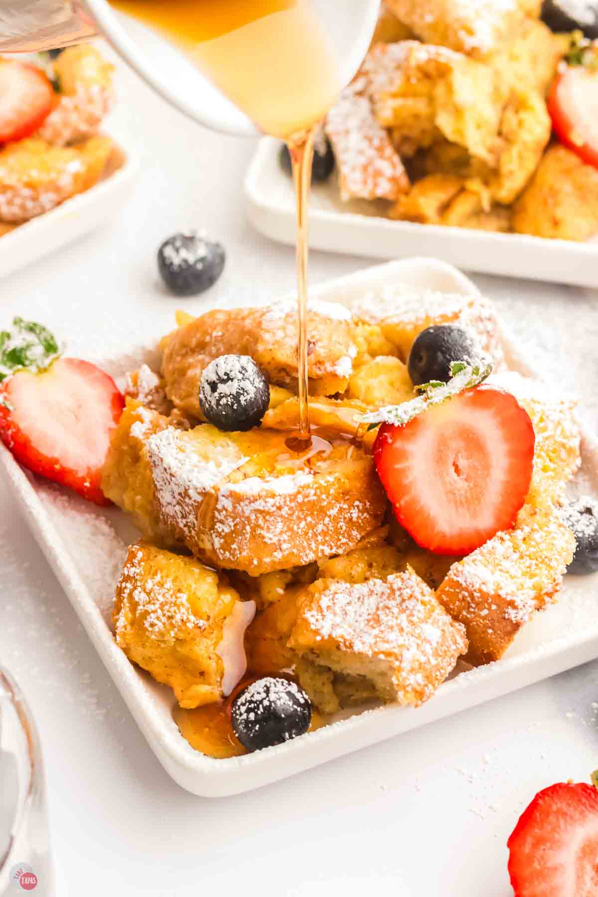 close up of syrup and bread with powdered sugar on top