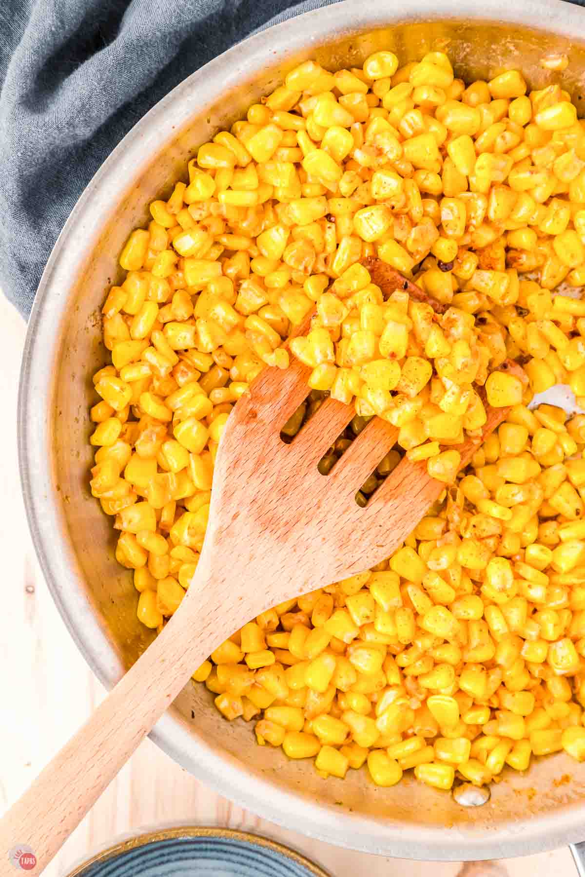 skillet of yellow corn with a wood spoon