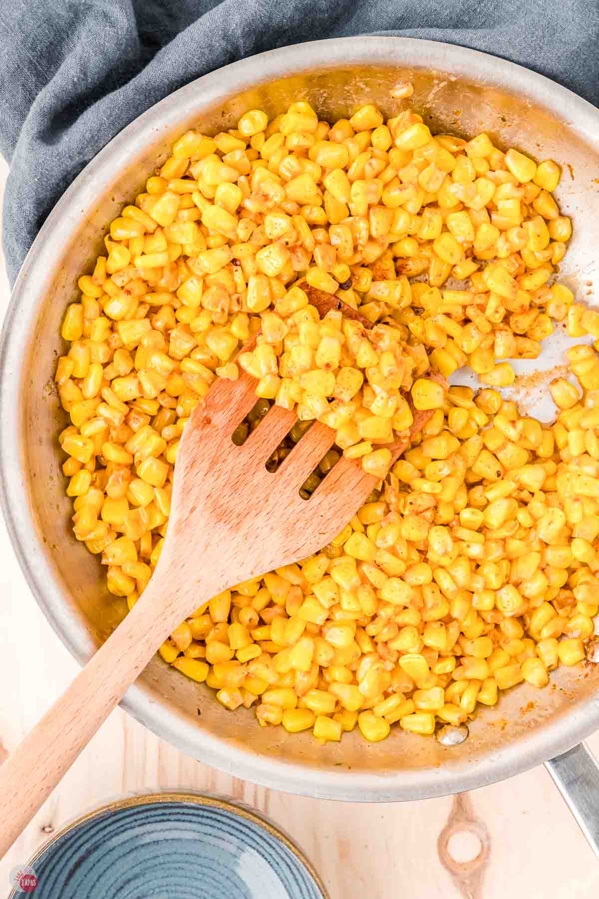 fried corn in a skillet and a wood spoon