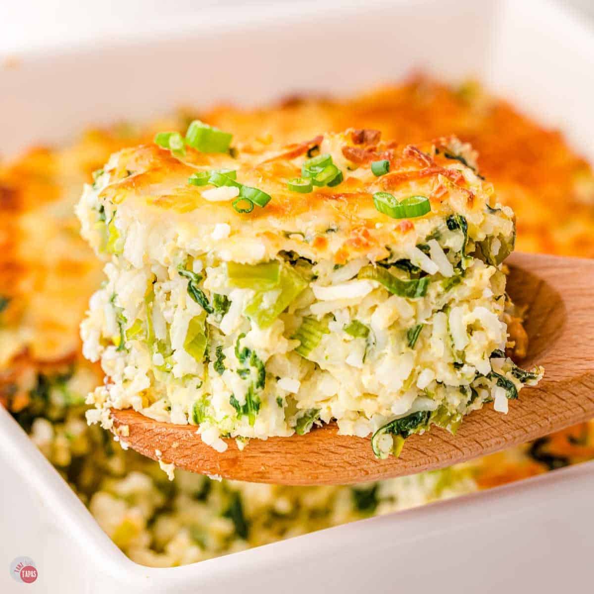 wood spoon with green rice casserole scoop on it