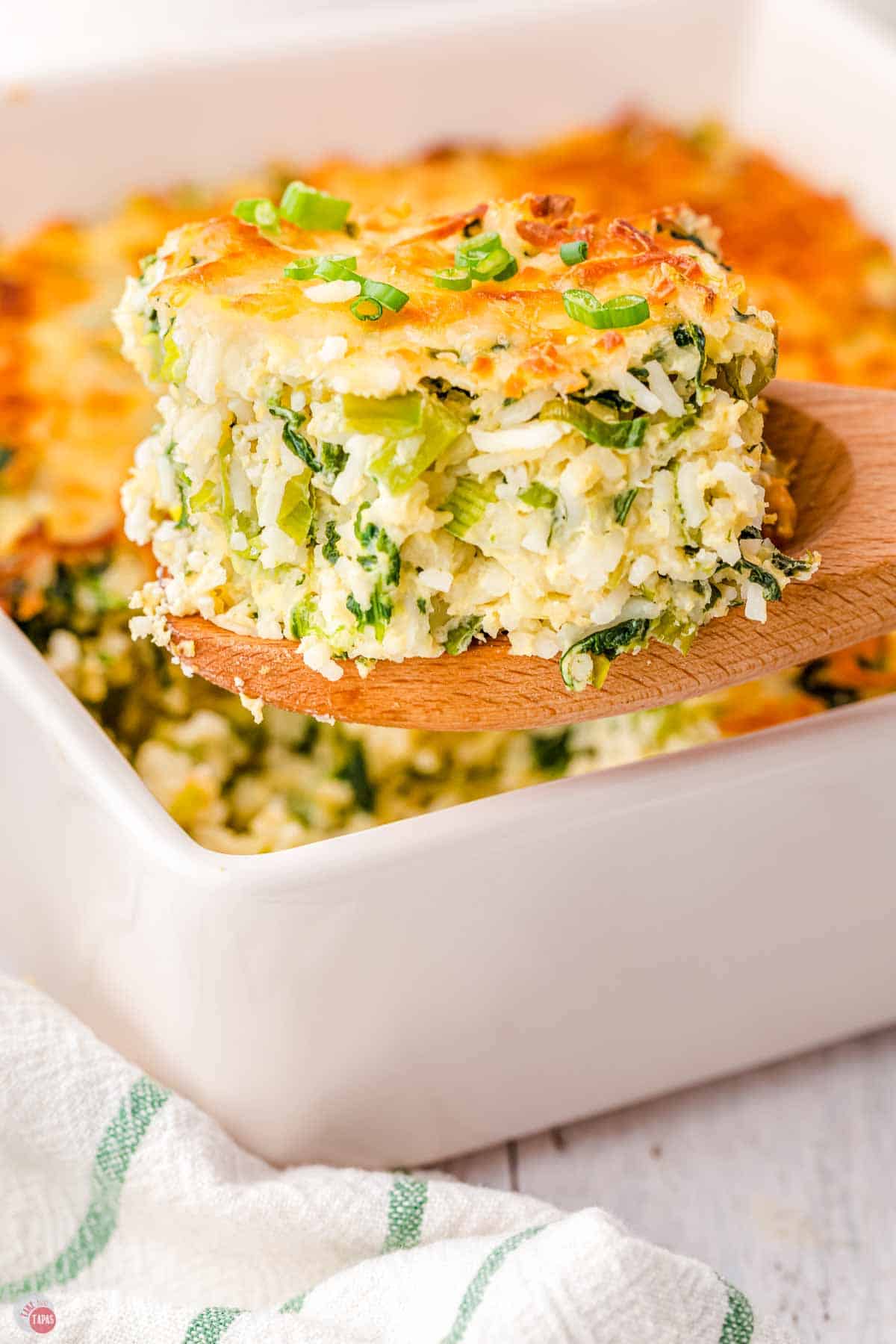 slice of rice casserole topped with cheese in a wood spoon