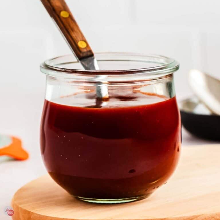jar of bbq sauce on a wood board with a spoon