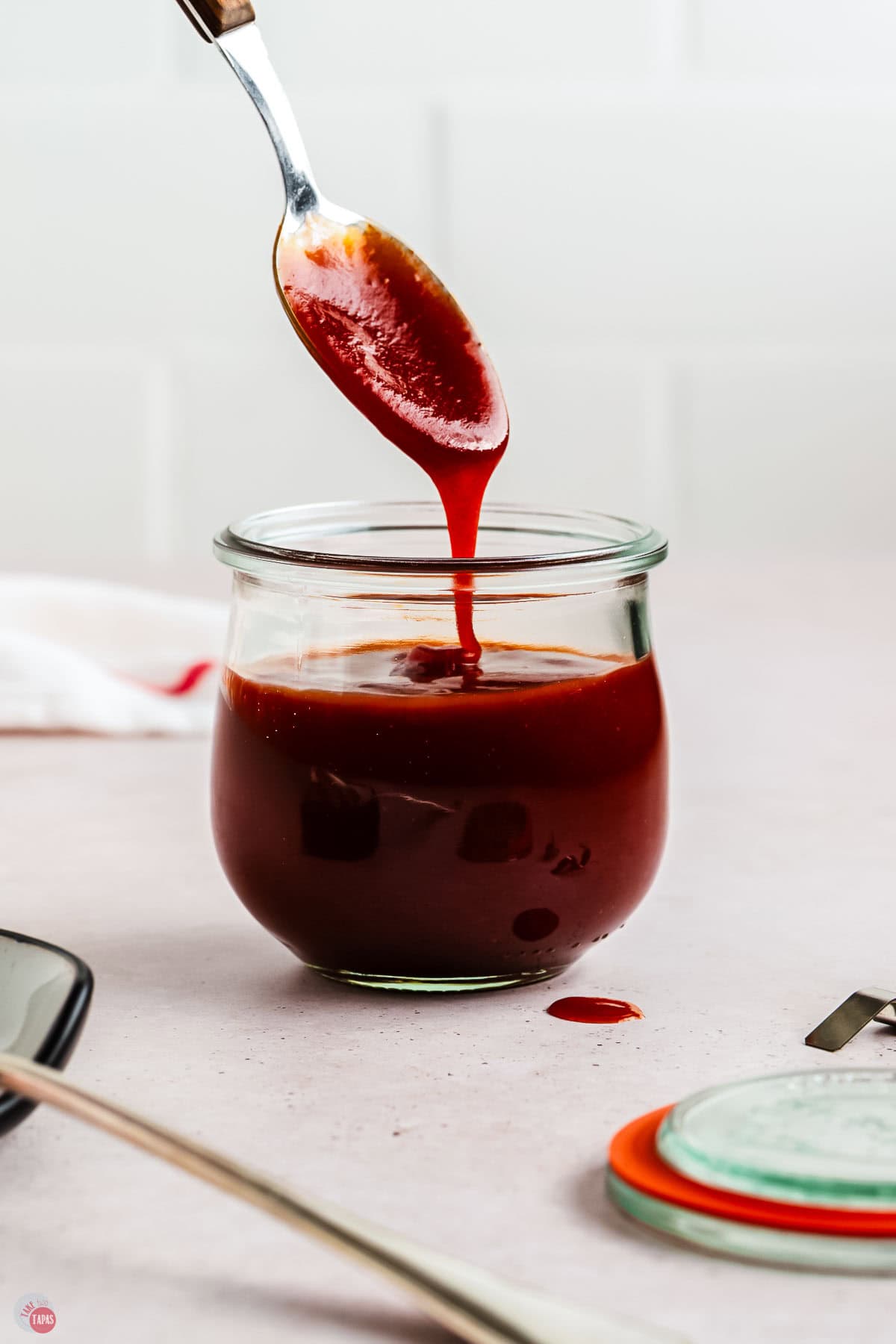 spoon dripping sauce back into a clear jar
