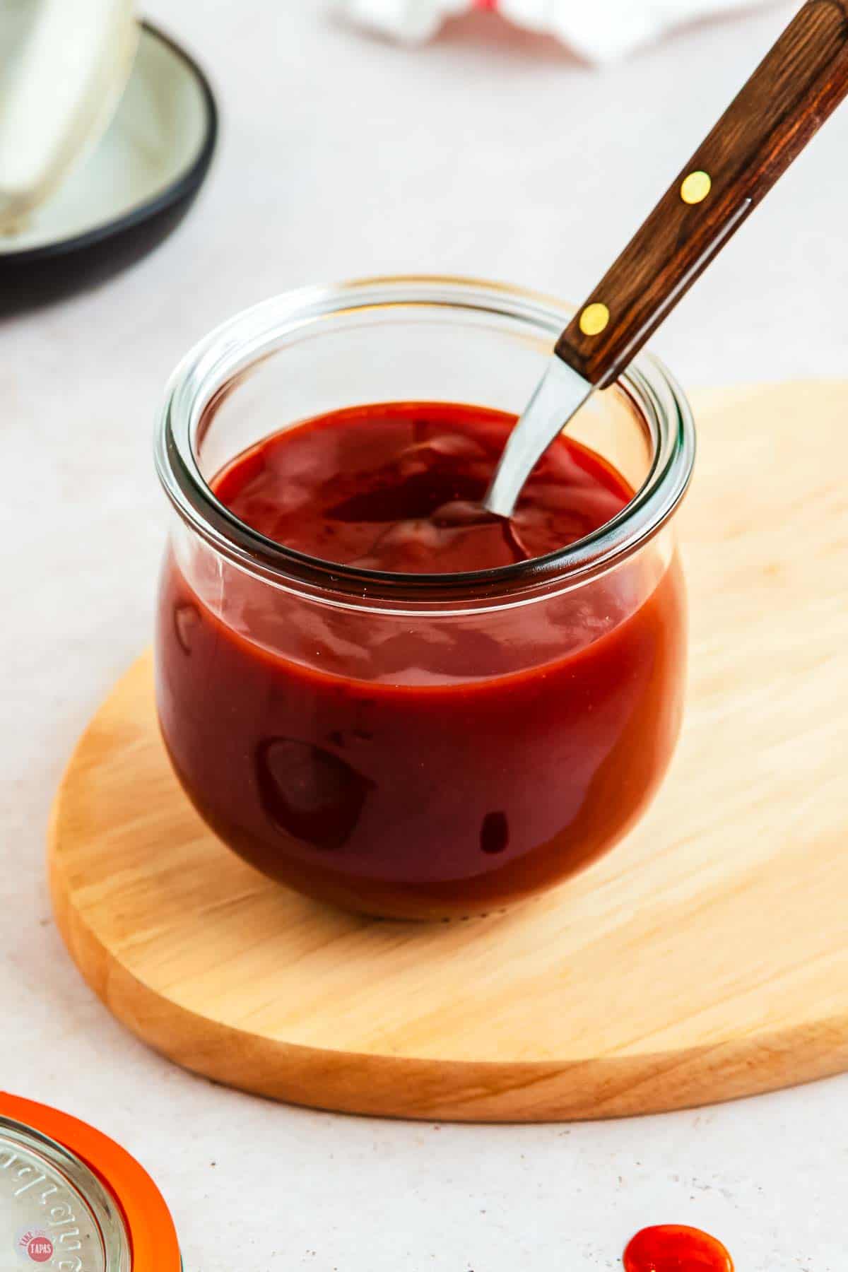 small clear jar of bbq sauce with a spoon