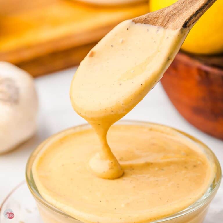 spoon dripping salad dressing back into a clear bowl