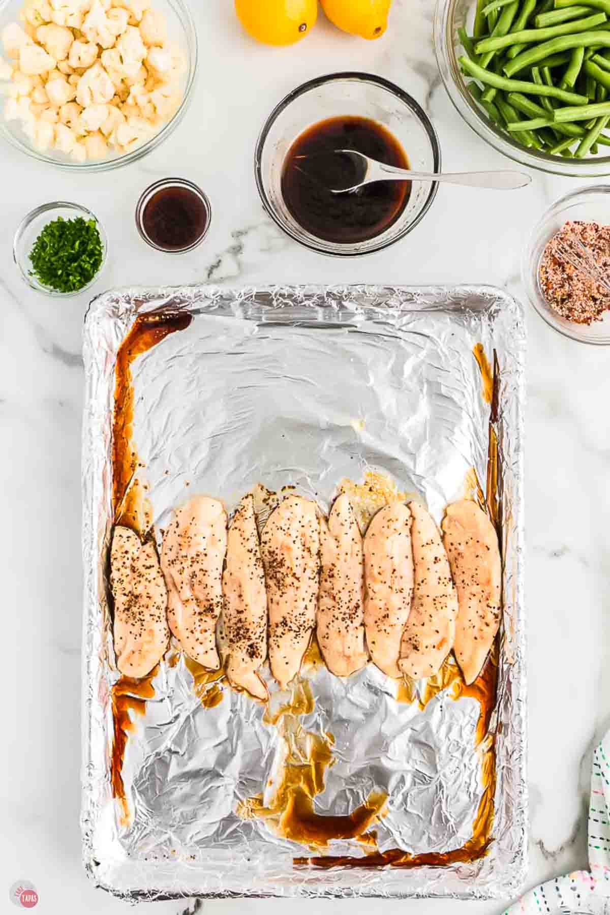 chicken tenders on a baking sheet with aluminum foil, drizzled with soy sauce