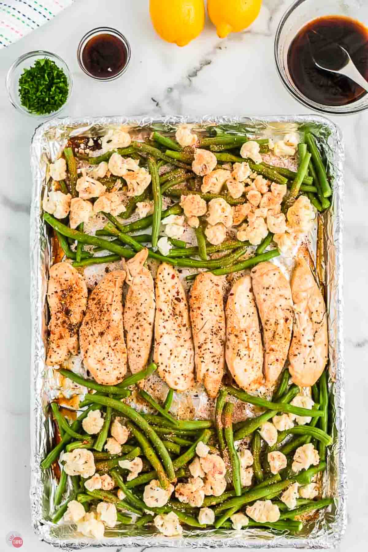chicken, green beans, and cauliflower florets on a caking sheet