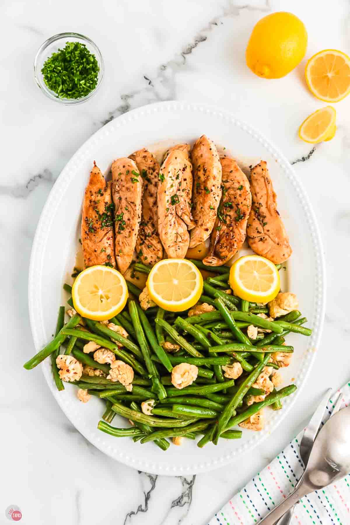 platter with chicken tenders, lemon, and green beans on it