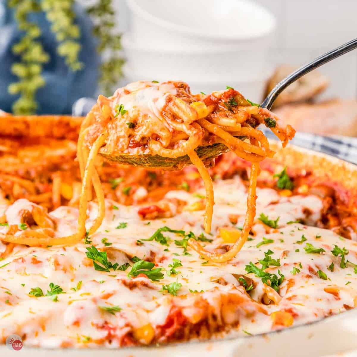 spoon scooping pasta and sauce out of a skillet