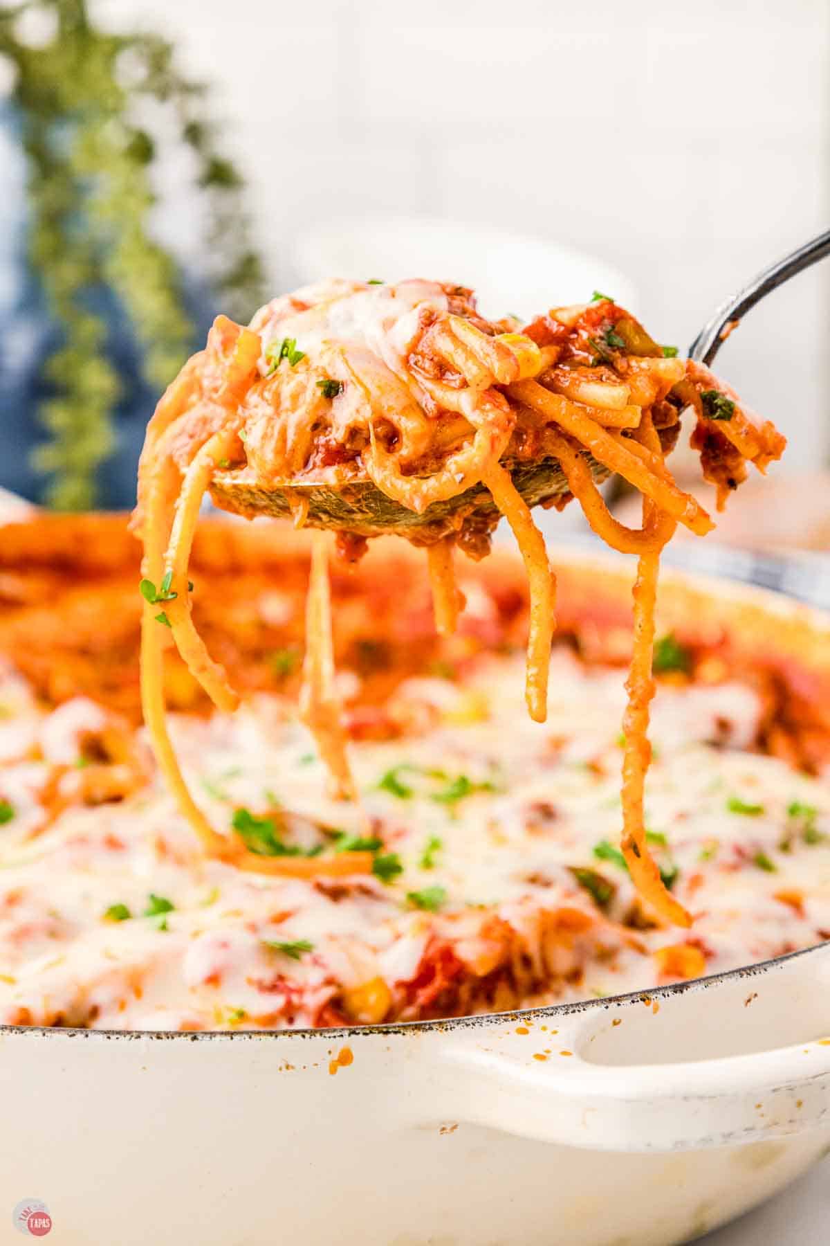 large spoon scooping spaghetti out of a skillet