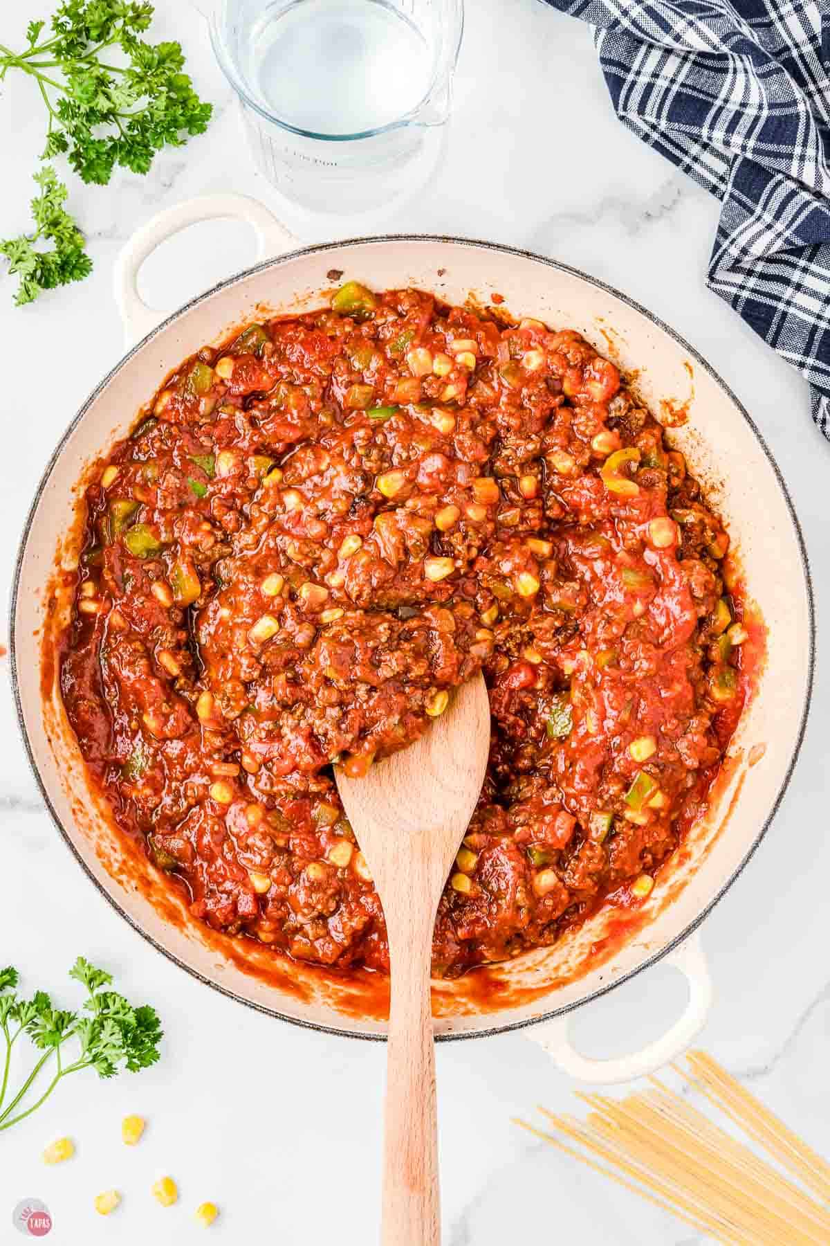 meat sauce in a skillet with a wood spoon