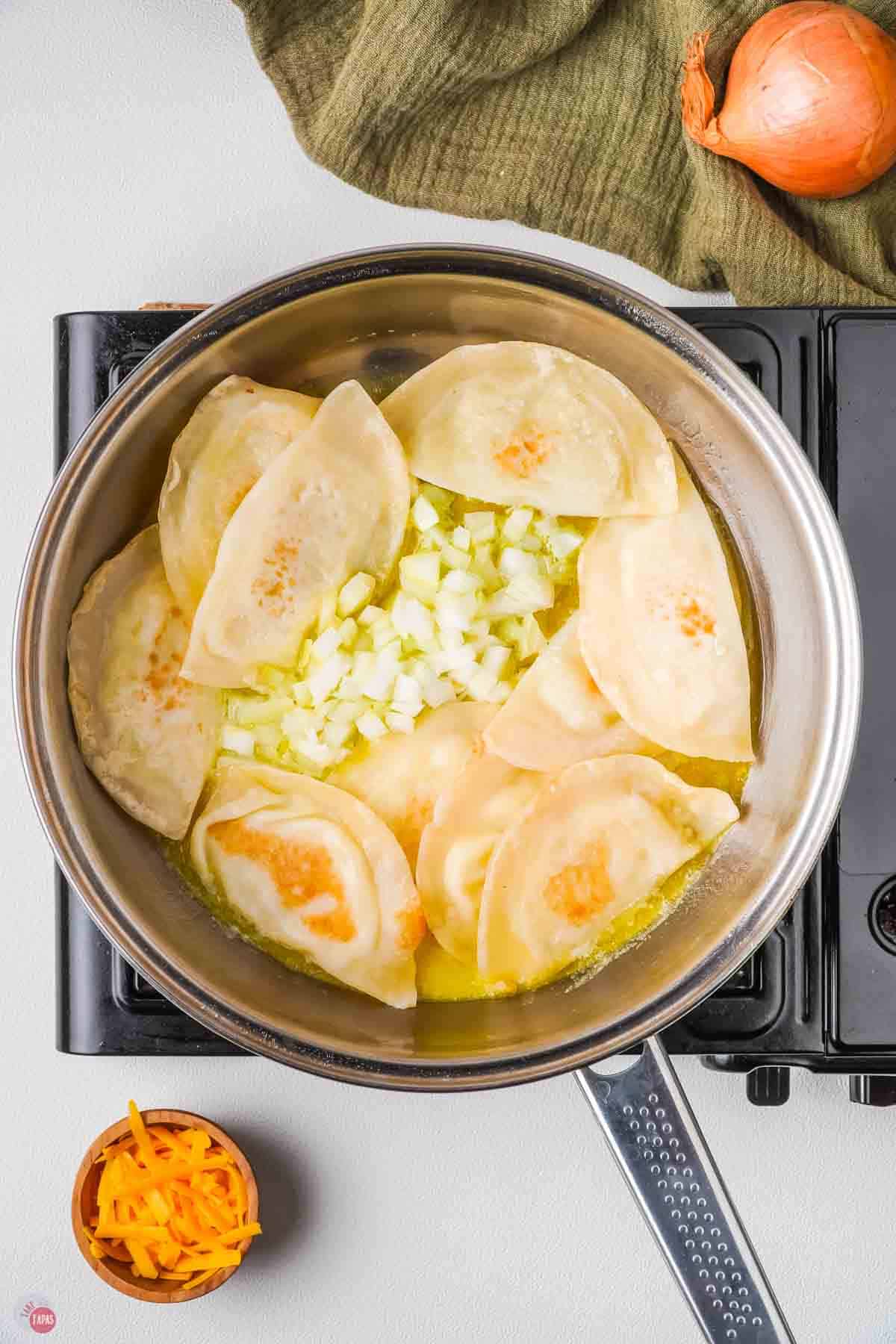 cheese pierogis in a pot with onion