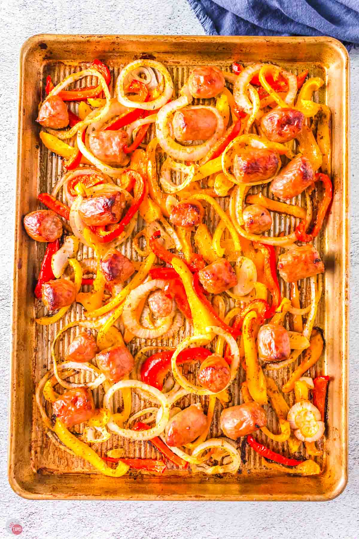 baked sausage with bell peppers and onions on a baking sheet