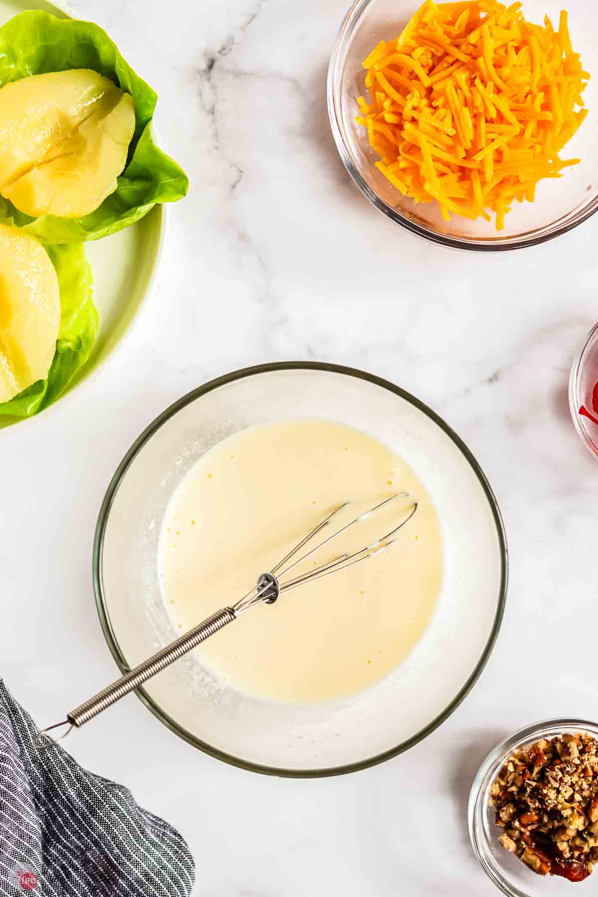 creamy salad dressing in a clear bowl with a whisk