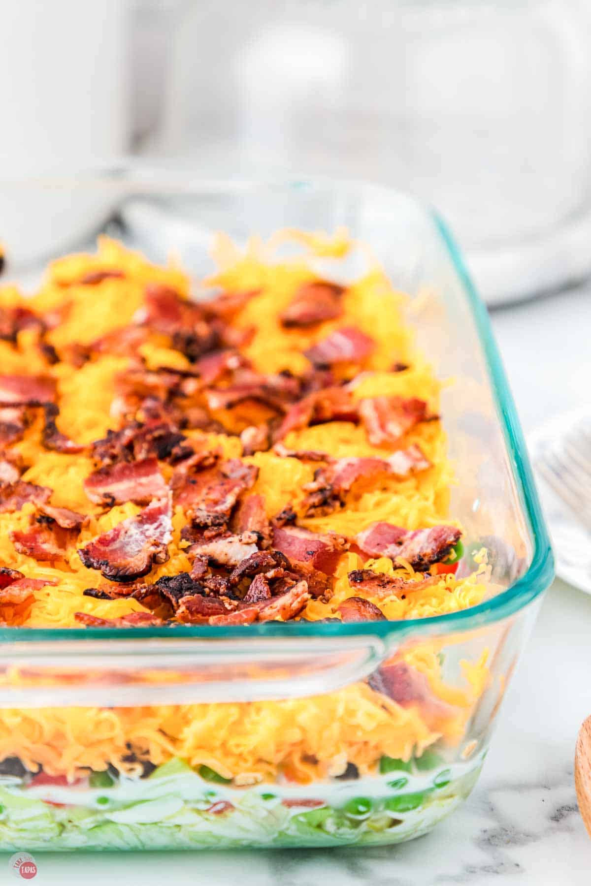 side view of clear casserole dish with a layered salad in it