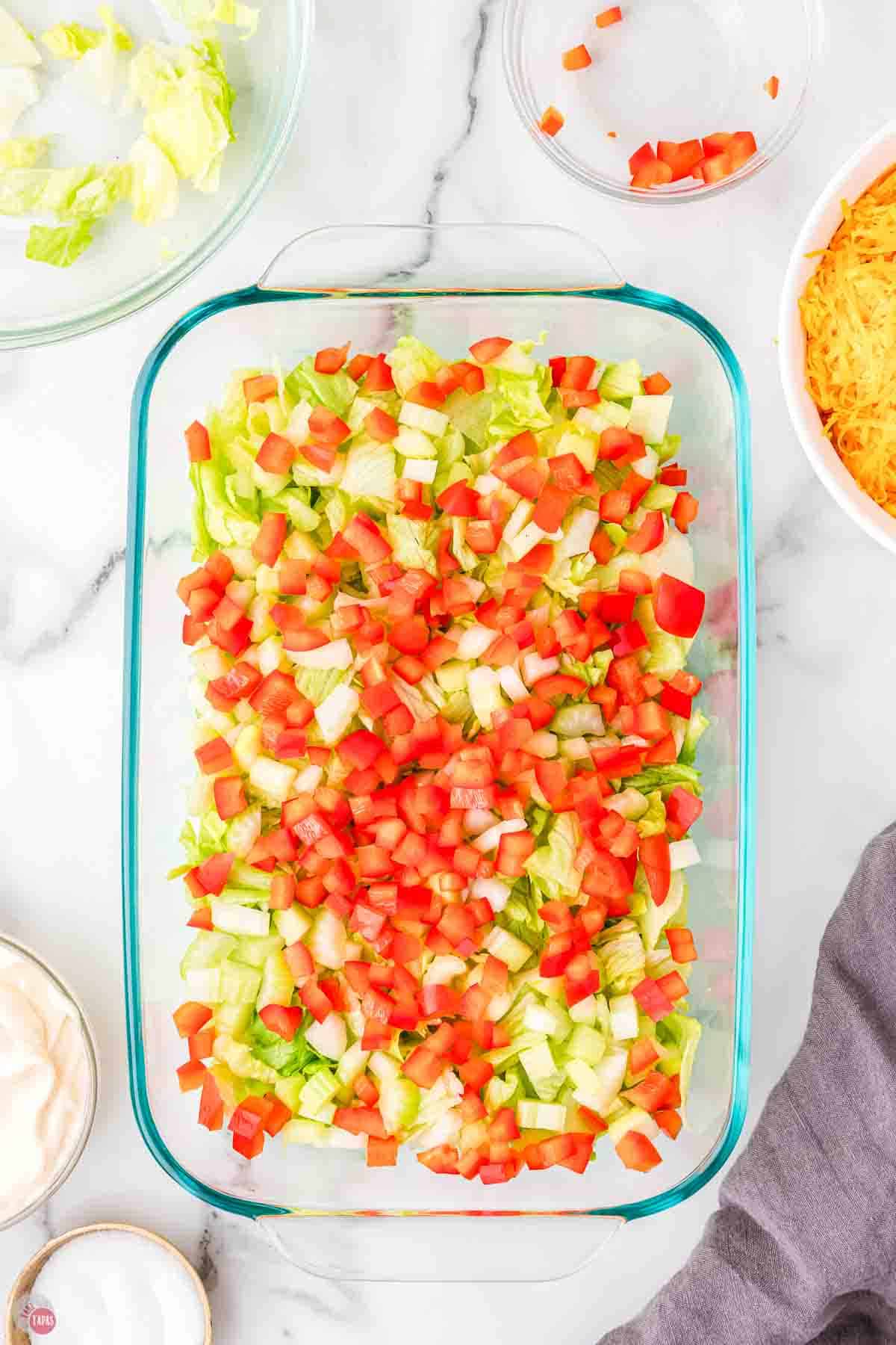 clear casserole dish with lettuce and diced tomatoes