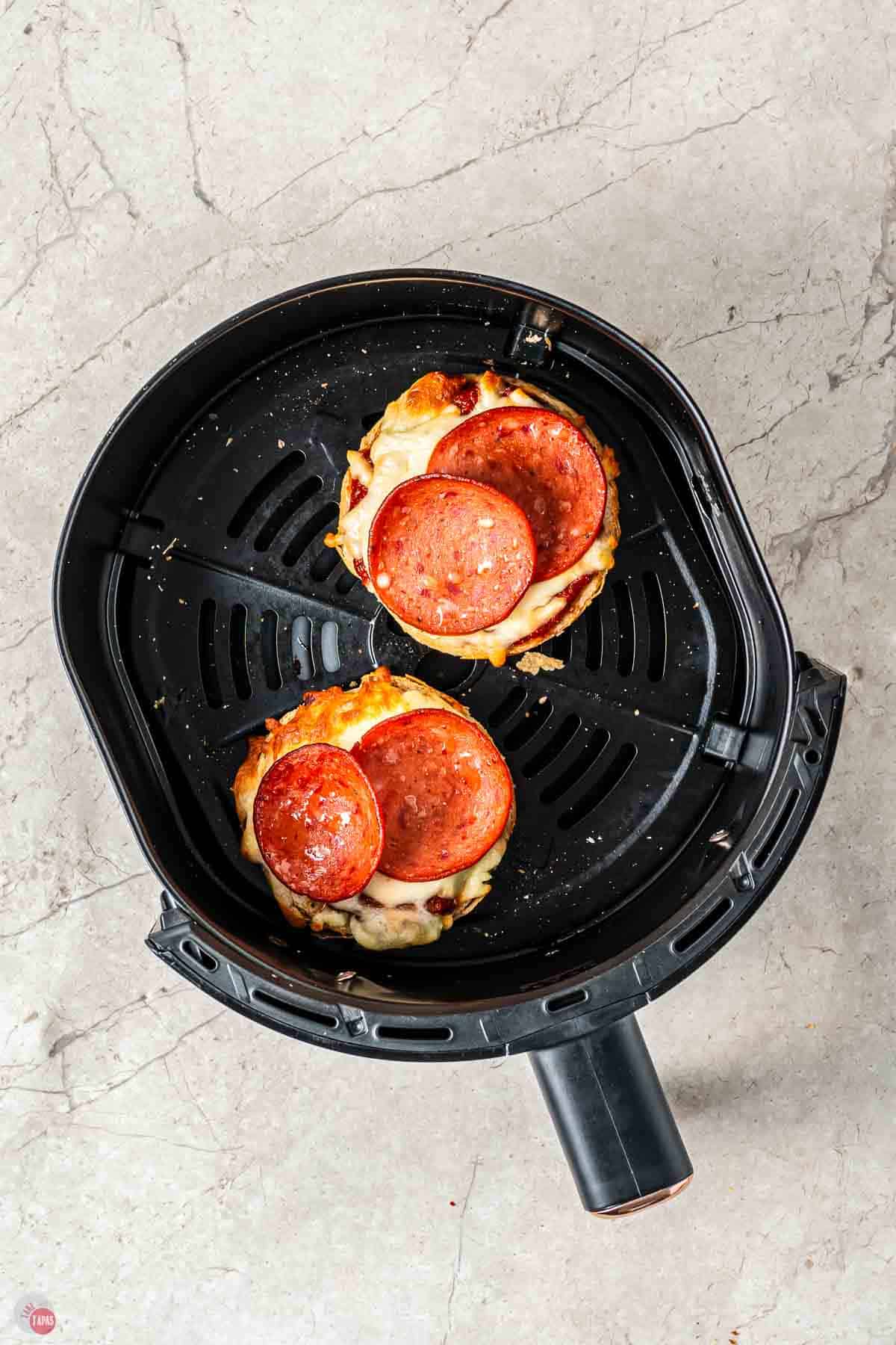 bagels topped with pepperoni in an air fryer basket