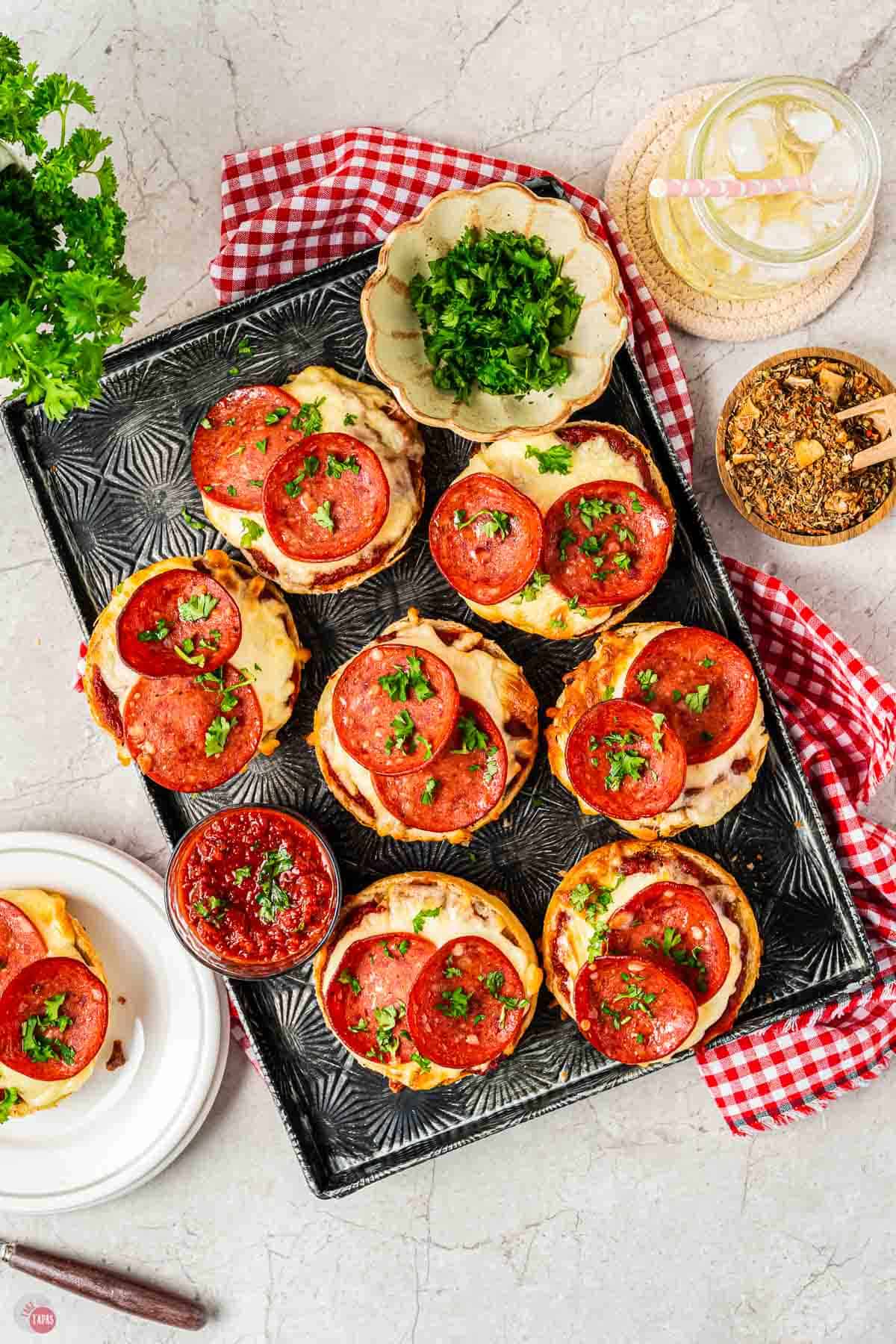 air fryer bagels on a black tray with small bowls of parsley and spices