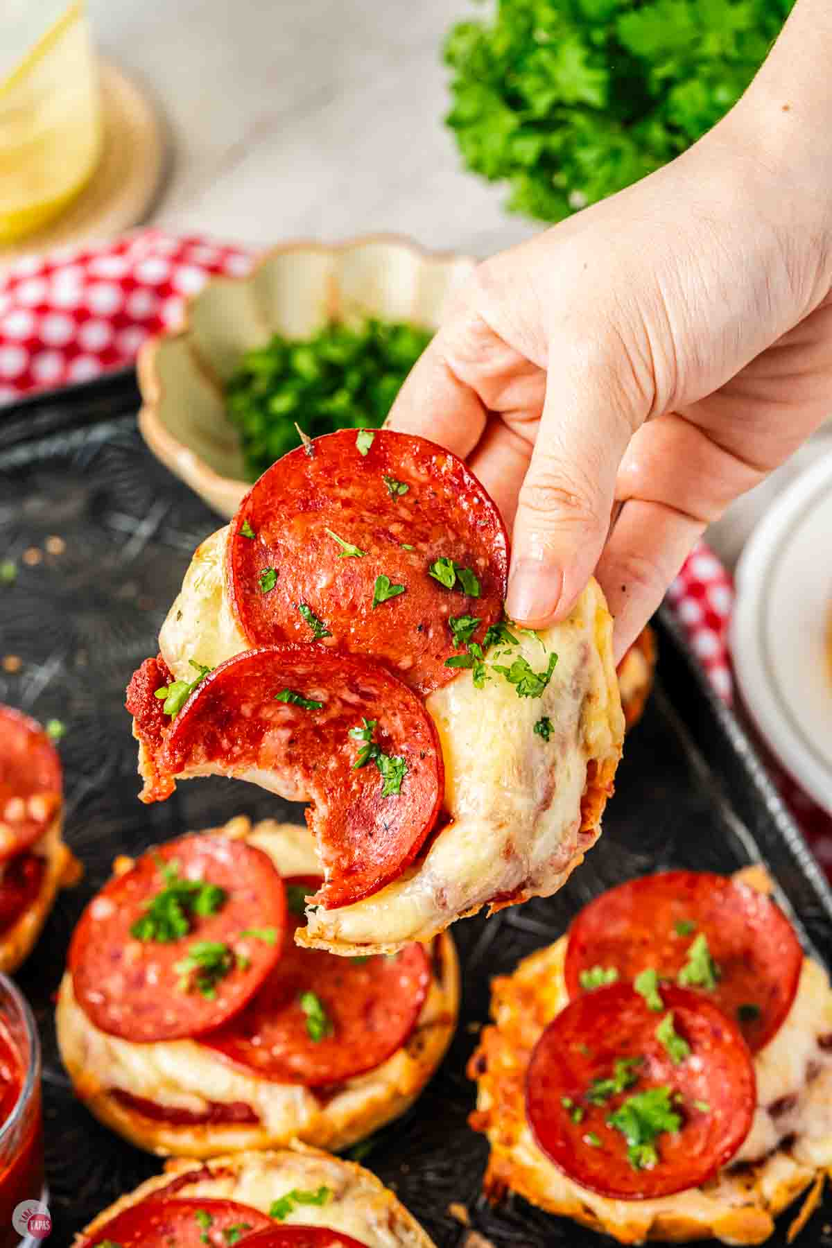 hand holding a pepperoni pizza bagel with a bite missing