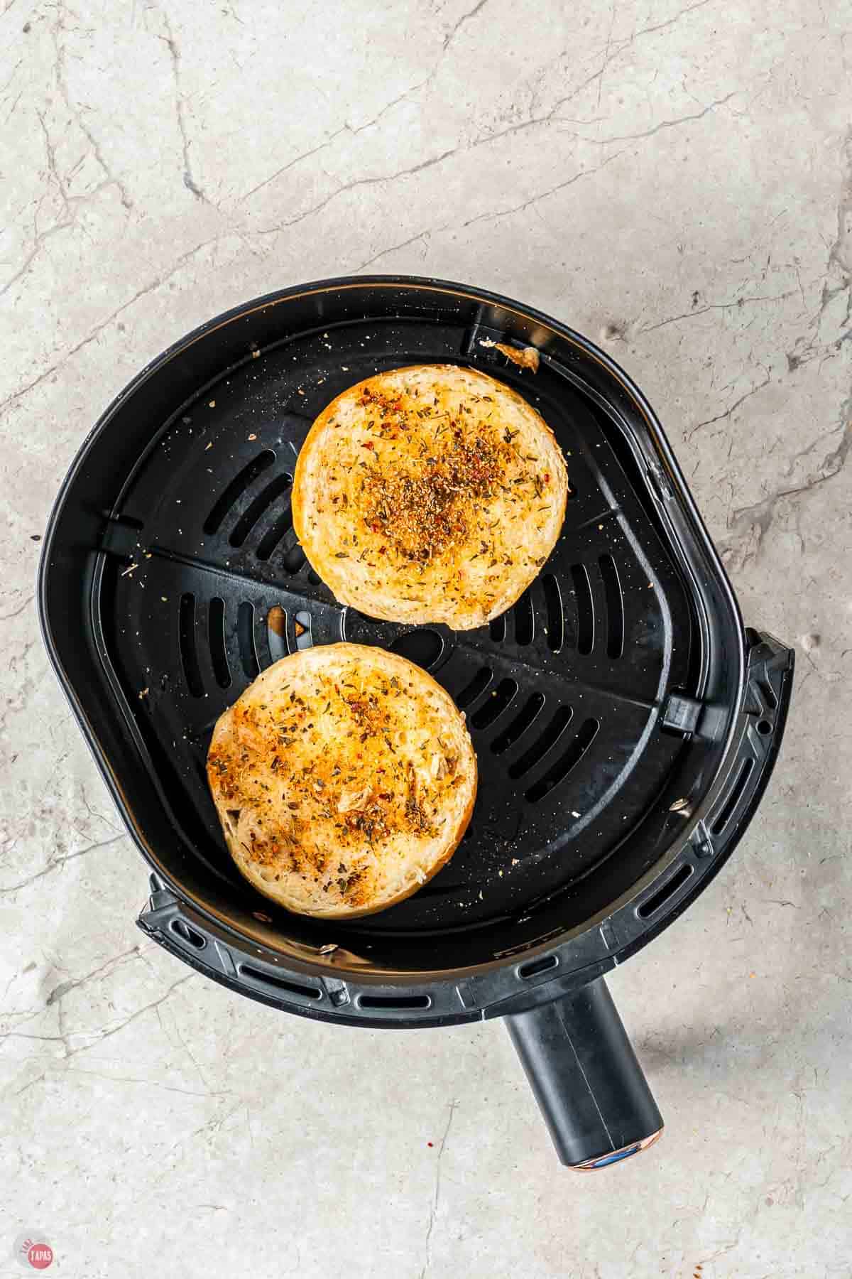 toasted bagel halves in an air fryer basket