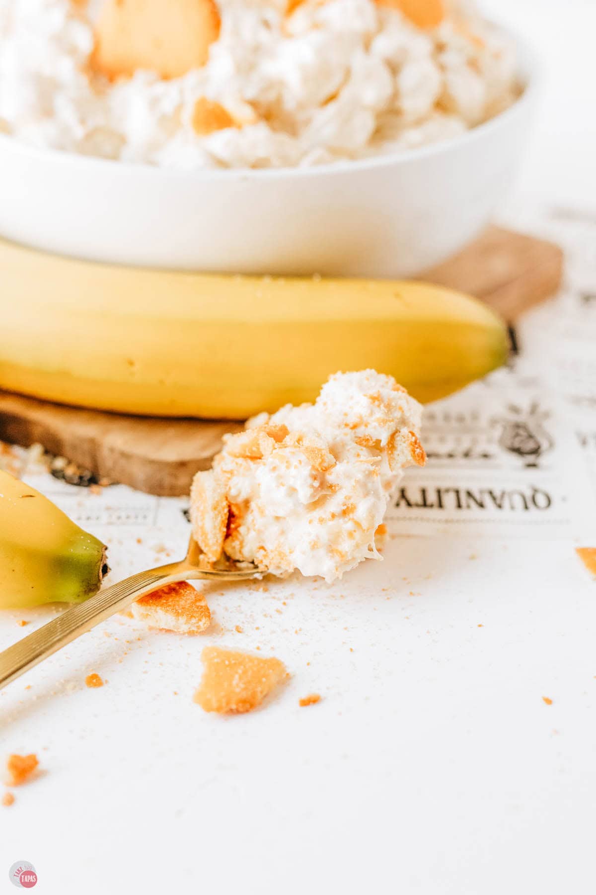 gold spoon with whipped cream on it and a banana in the background