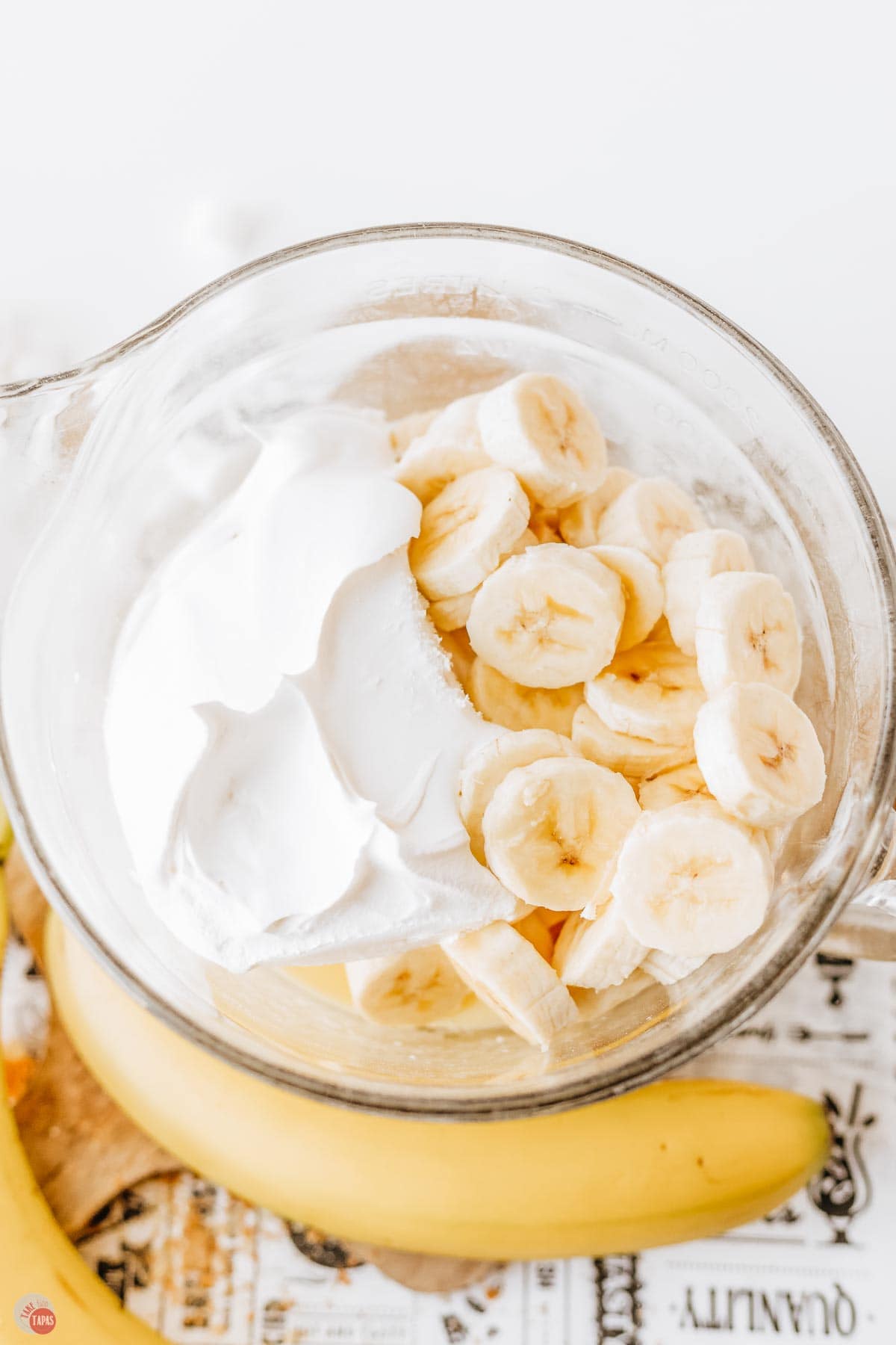 clear bowl with whipped cream and sliced bananas in it
