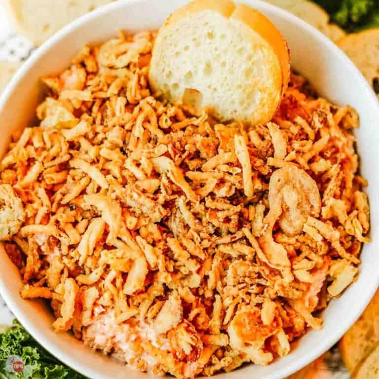 white bowl full of dip topped with fried onions