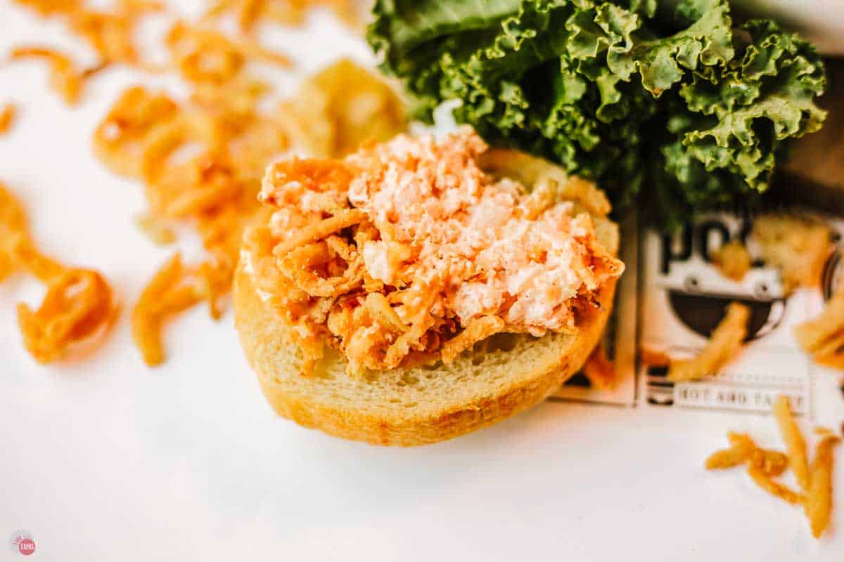 small crostini with an orange spread on it next to a piece of kale