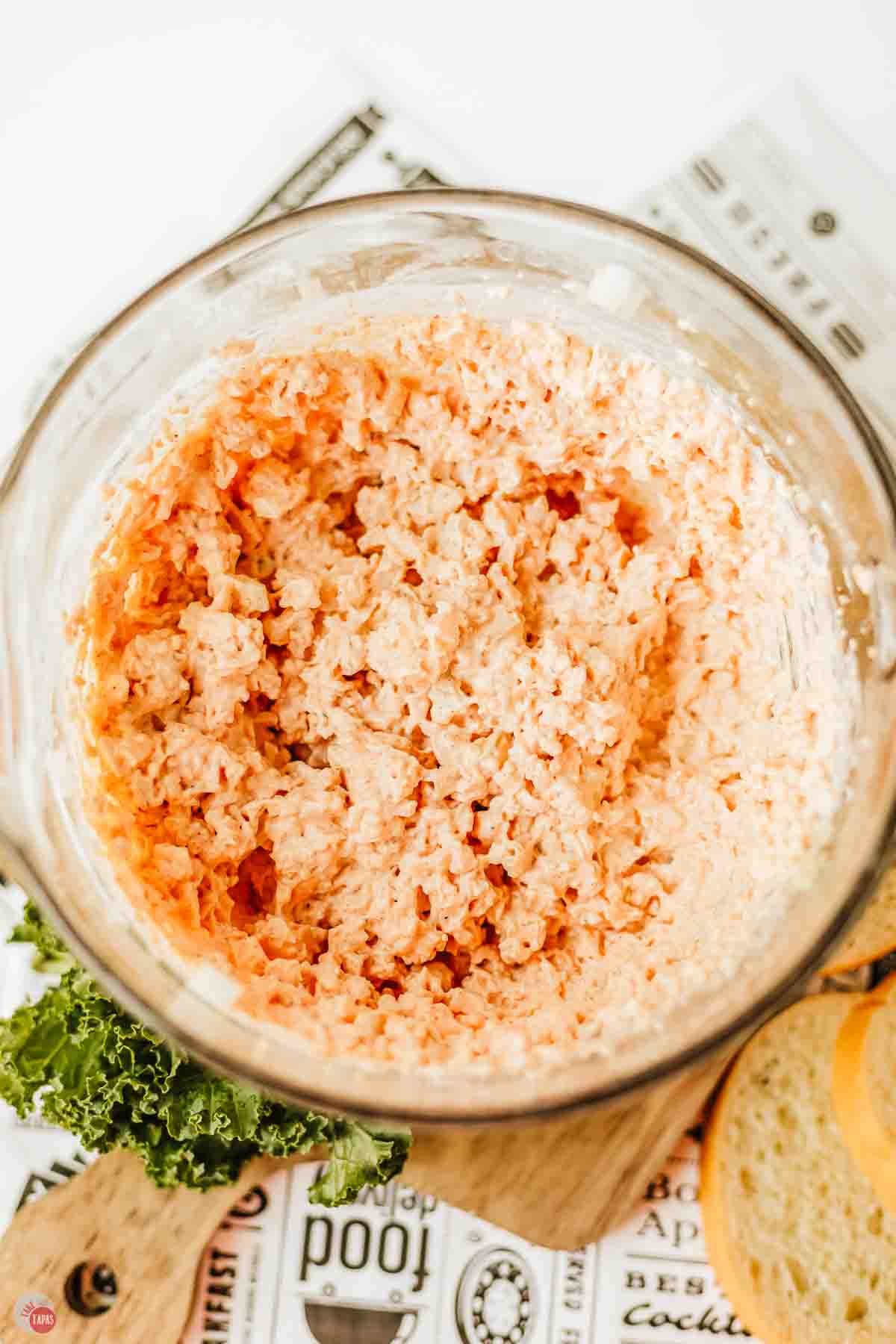 orange colored dip being mixed in a clear bowl