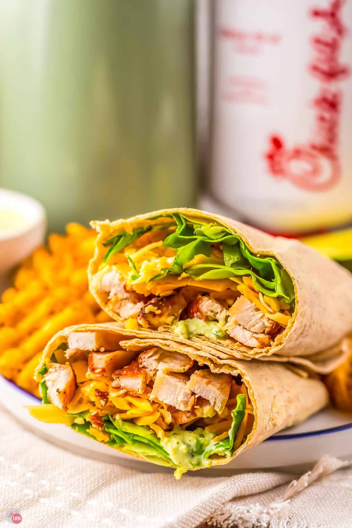 sliced chicken wrap next to waffle fries