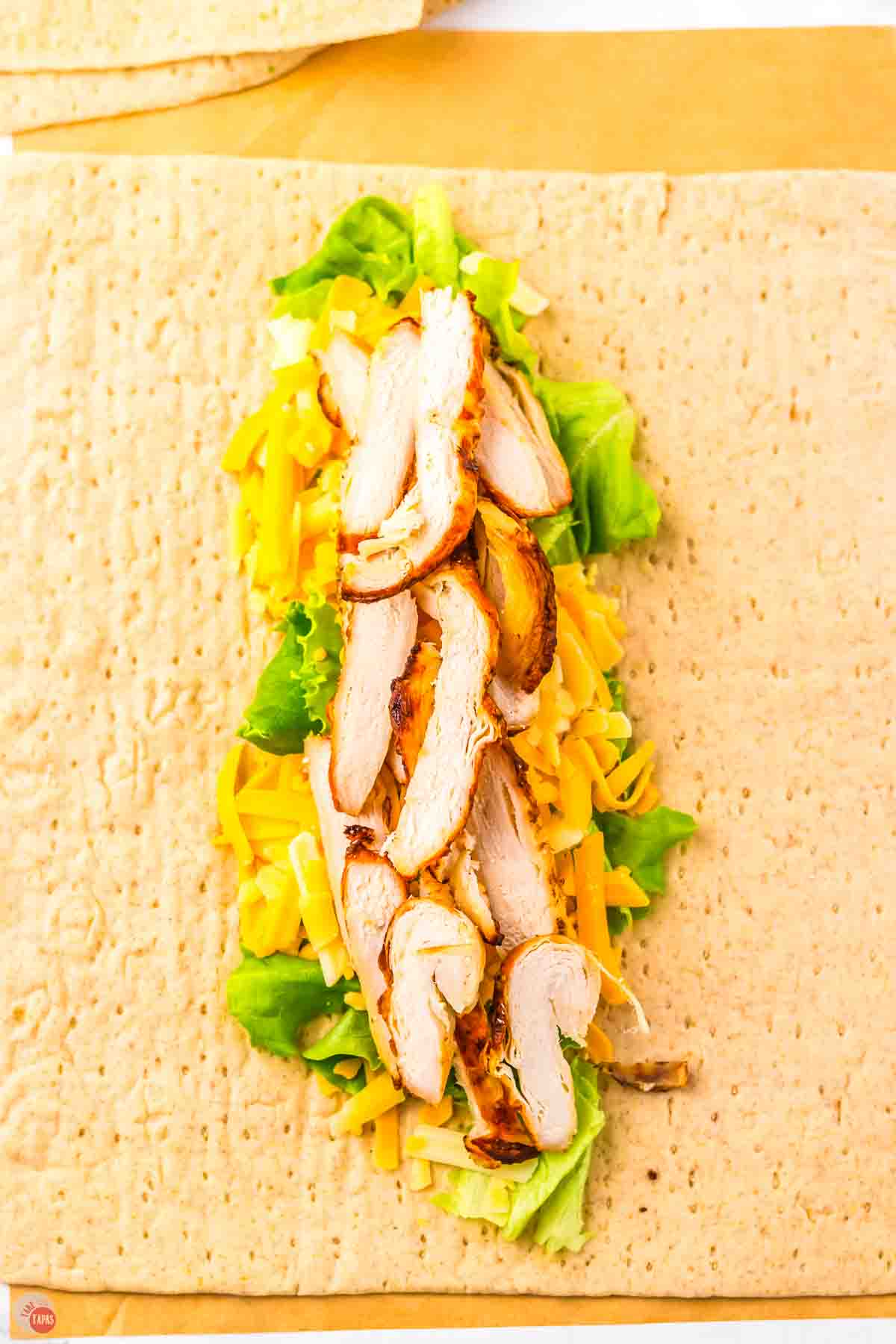 sliced chicken, cheese, and lettuce on a flatbread wrap
