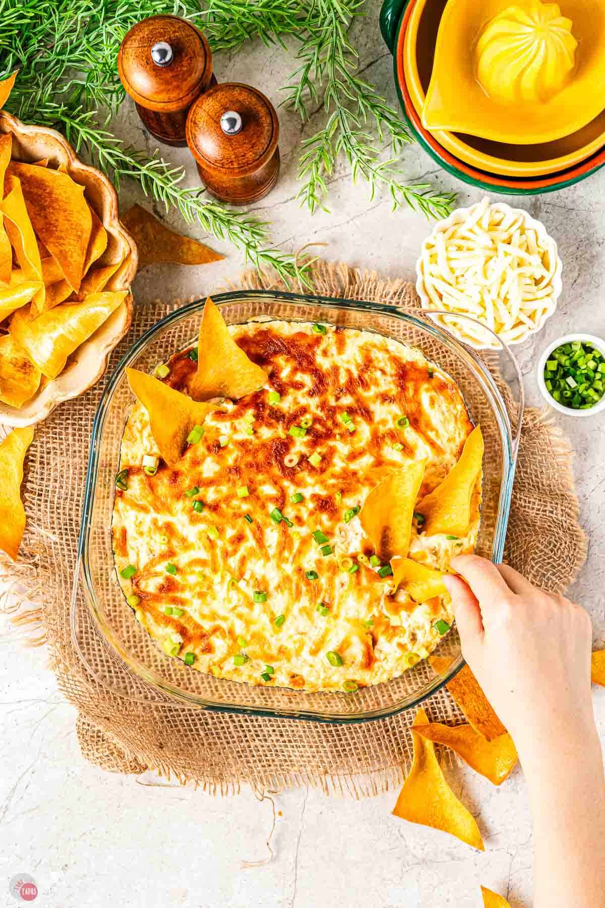bowl of baked dip with hand scooping some out
